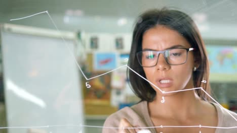 Young-attractive-female-office-worker-writing-on-glass-whiteboard