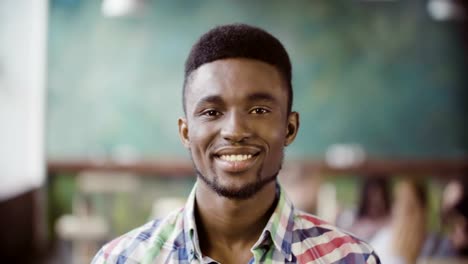 Portrait-of-young-successful-African-businessman-at-busy-office.-Handsome-male-looking-at-camera-and-start-smiling