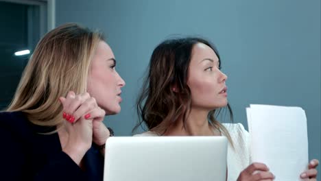 Two-female-managing-directors-discussing-ideas-of-project-while-sitting-on-conference-in-office-hall