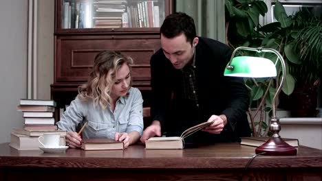 Happy-young-professor-and-smiling-female-student-discussing-the-book-for-research