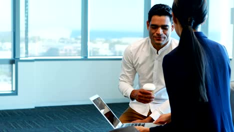 Business-colleagues-discussing-over-laptop