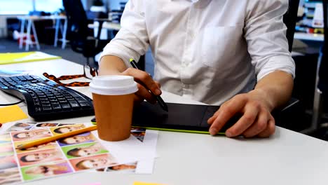 Male-graphic-designer-working-on-graphic-tablet-at-desk