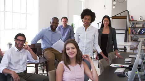 Young-business-colleagues-smiling-to-camera-in-their-office