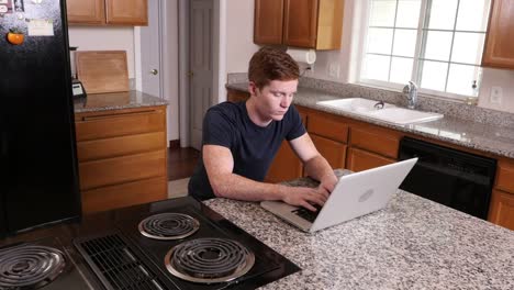 Junger-Mann,-arbeiten-am-Computer-in-Küche