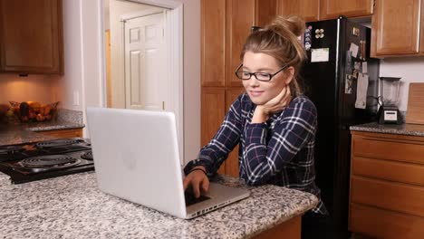 Young-woman-working-oncomputer-in-kitchen