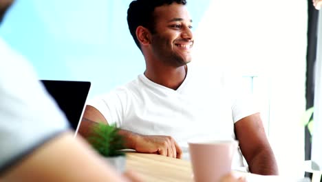 Cheerful-hindu-man-sitting-at-the-table-with-his-colleagues