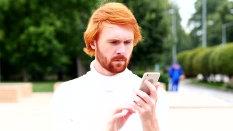 Smartphone-für-Online-Surfen,-Mann-mit-roten-Haaren,-im-Freien-verwenden