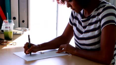 Female-executive-writing-on-paper-at-her-desk-4k