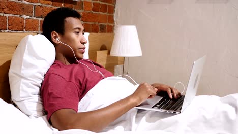 Video-Chat-for-Work-by-Young-African-Man-Lying-in-Bed-at-Night