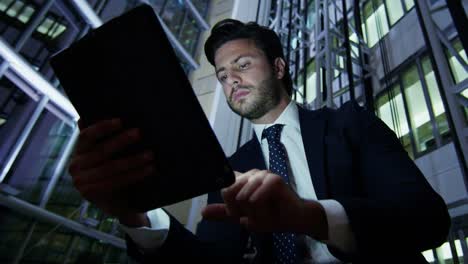 European-businessman-hotel-atrium-night-using-tablet-device