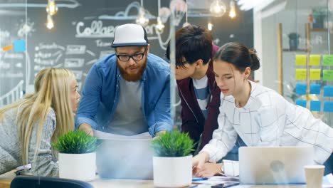 Equipo-diverso-de-mujeres-jóvenes-y-hombres-desarrolladores-tienen-reunión-de-equipo-con-ordenador-portátil.-Hermosos-jóvenes-en-ambiente-de-oficina-moderno-brillante.