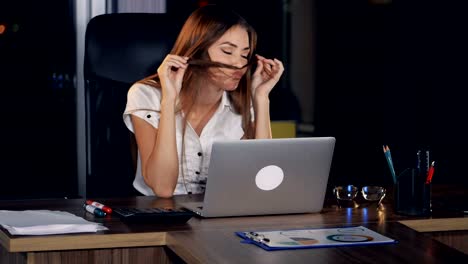 Eine-Geschäftsfrau-zieht-ihre-Brille-auf-einen-Laptop.