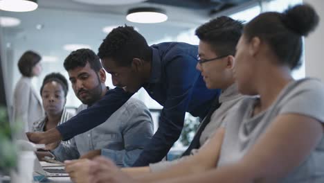 African-Man-Showing-Report-on-Laptop-to-Coworkers