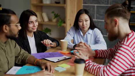 Junge-Hipster-Mann-diskutieren-neue-Gründungsvorhaben-mit-multiethnischen-Team-im-modernen-Büro