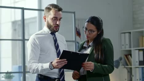 Jóvenes-colegas-hablar-de-negocios-papel-en-portapapeles