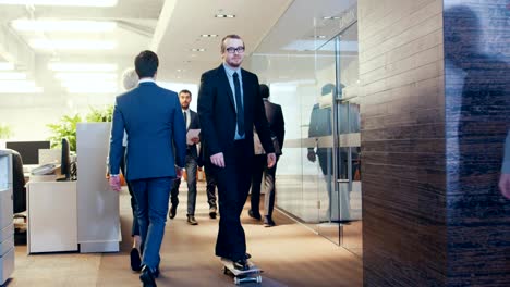 Stylish-Suited-Businessman-Rides-Skateboard-Through-the-Corporate-Building-Hallway.-Stylish-Glass-and-Concrete-Building-with-Multicultural-Crowd-of-Business-People.