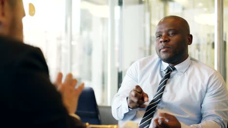 African-American-businessman-gesticulating-and-explaining-his-startup-details-to-investor-in-formal-wear-in-glassy-cafe-during-lunch-time