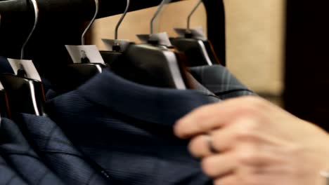 Man-choosing-a-suit-at-tailor's-shop