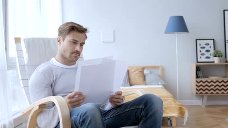 Adult-Man-Reading-Documents-while-Sitting-on-Relaxing-Chair