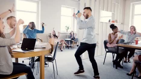 Camera-follows-happy-businessman-walk-into-office,-doing-funny-celebration-dance.-Multi-ethnic-workers-laugh-and-clap-4K