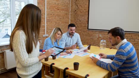 Kreative-Business-Team-treffen-Frau-Manager-präsentiert-Finanzdaten-an-die-Aktionäre-mit-digital-Tablette-in-lässig-moderne-Büro-Tagungsraum-mit-Tageslicht