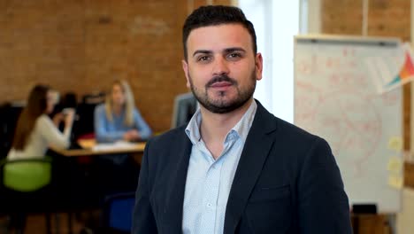 Portrait-of-successful-Businessman-entrepreneur-working-at-busy-office-smiling