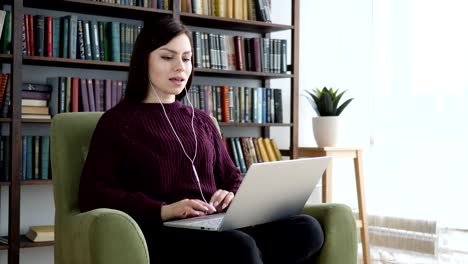 Casual-Sitting-Woman-Listening-Music-in-headphones-and-Enjoying