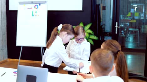 Girl-in-the-person-of-the-director-looks-at-the-business-report-of-his-colleague.-They-discuss-development-plans-together.-Business-children