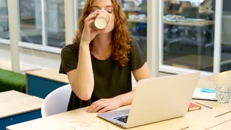 Businesswoman-using-laptop-while-having-coffee-4k