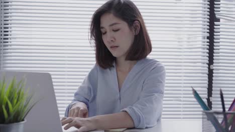 Hermosa-joven-sonriente-mujer-asiática-trabajando-en-ordenador-portátil-mientras-está-sentado-en-una-sala-de-estar-en-casa.-Mujer-de-negocios-asiáticos-trabajando-en-su-oficina-en-casa.-Disfrutando-en-casa.