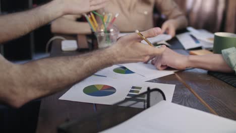 Close-up-of-business-hands-team-working-on-statistical-data-at-table