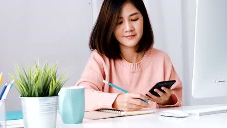 Mujer-de-negocios-usando-la-aplicación-Nota-smartphone-y-depósito-en-la-oficina-en-casa.