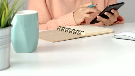 Young-asian-women-business-owners-using-app-smartphone-and-take-notes-in-office.