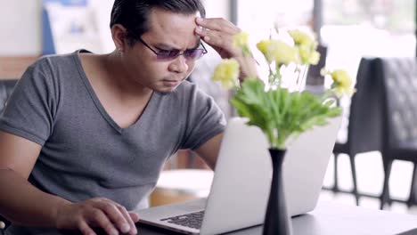 man-under-a-lot-of-stress-using-laptop-computer-in-cafe