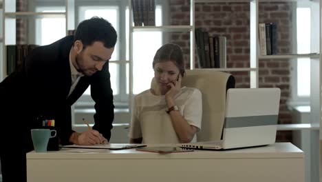 Portrait-of-a-woman-making-a-phone-call-while-her-colleague-is-working-in-a-office