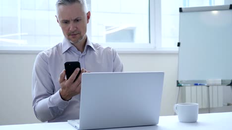 Middle-Aged-Businessman-Busy-Using-Smartphone-for-Work-in-Office