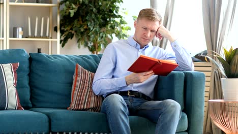 Sleeping-Middle-Aged-Man-Holding-Book-while-Sitting-on-Sofa