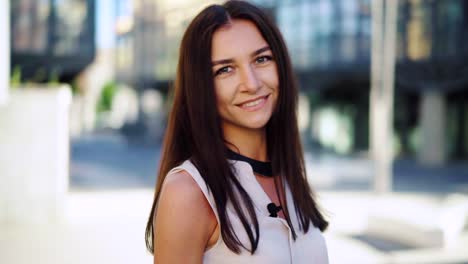 Businesswoman-walking-towards-camera-speak-and-smiles,-outside-office-building