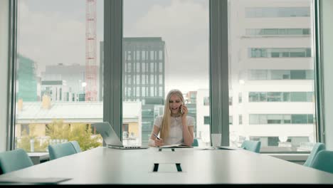 Businesswoman-waving-with-hand-while-speaking-on-phone.-Stylish-businesswoman-having-phone-call-while-sitting-at-table-in-conference-hall-and-waving-with-hand-greeting-colleague