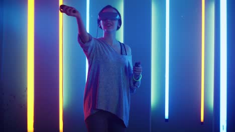 Beautiful-Young-Girl-Wearing-Virtual-Reality-Headset-Draws-Abstract-Lines-and-Figures-with-Joysticks-/-Controllers.-Creative-Young-Girl-Does-Concept-Art-with-Augmented-Reality.-Playing-Online-Video-Game.-Neon-Retro-Lights-Surround-Her.