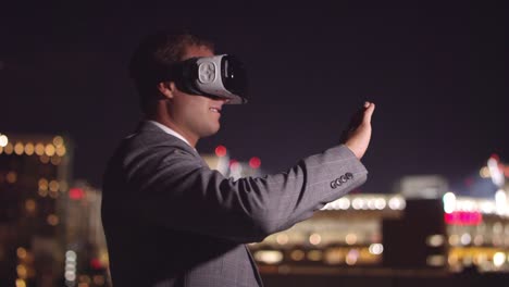 Young-business-man-wearing-VR-headset-at-night-swiping-screen-with-hand-gestures