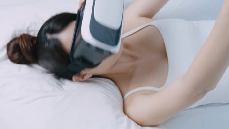 Woman-watching-virtual-reality-device-on-bed