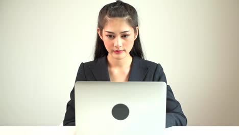 Business-woman-typing-on-laptop.-Young-beautiful-asian-business-woman-in-suit-typing-on-laptop-in-front-of-camera.