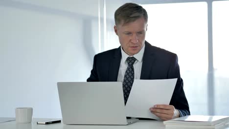 Businessman-Working-on-Documents-and-Laptop