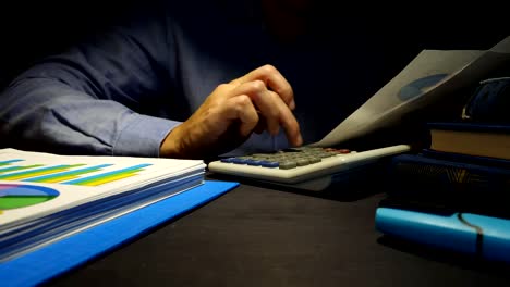 Businessman-uses-calculator-for-checking-financial-report.