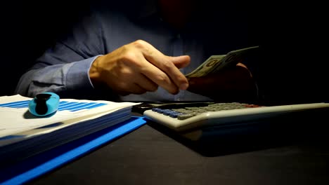 Man-is-counting-dollar-banknotes-and-using-calculator.-Loans-in-the-office.