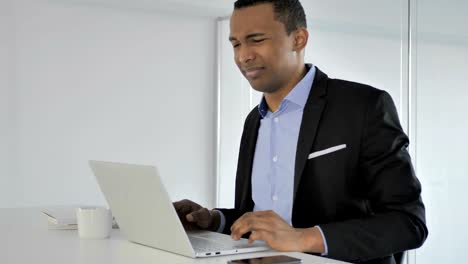 Casual-Afro-American-Businessman-with-Neck-Pain-working-on-Laptop