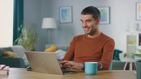 Retrato-de-sonriente-guapo-trabajando-en-ordenador-portátil,-sentado-en-su-escritorio-de-madera-en-casa.-Hombre-navegando-por-Internet,-trabajando-en-la-Notebook-de-su-oficina-de-sala-de-estar.