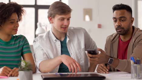 hombre-mostrando-smartphone-a-compañeros-de-trabajo-en-oficina