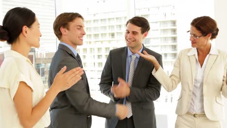 Business-people-shaking-hands-at-interview-while-others-applaud